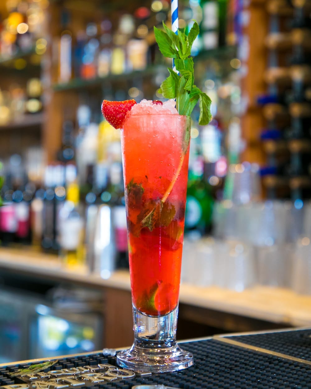 A tall red cocktail on a bar
