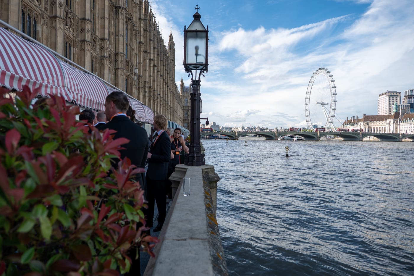 Guests on the terrace by the Thames at Westminster, the London Eye behind