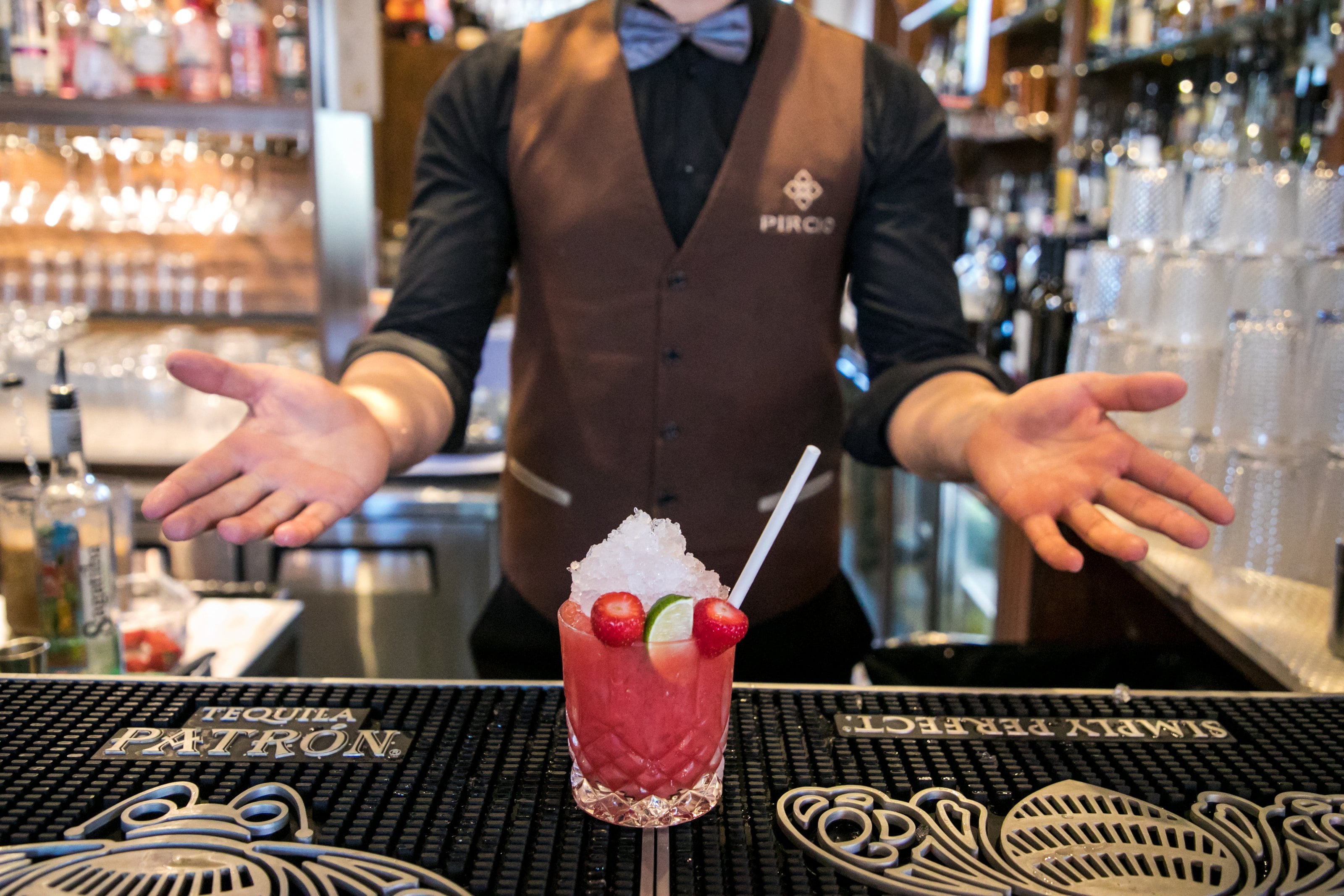 A bartender presenting a red cocktail on the bar