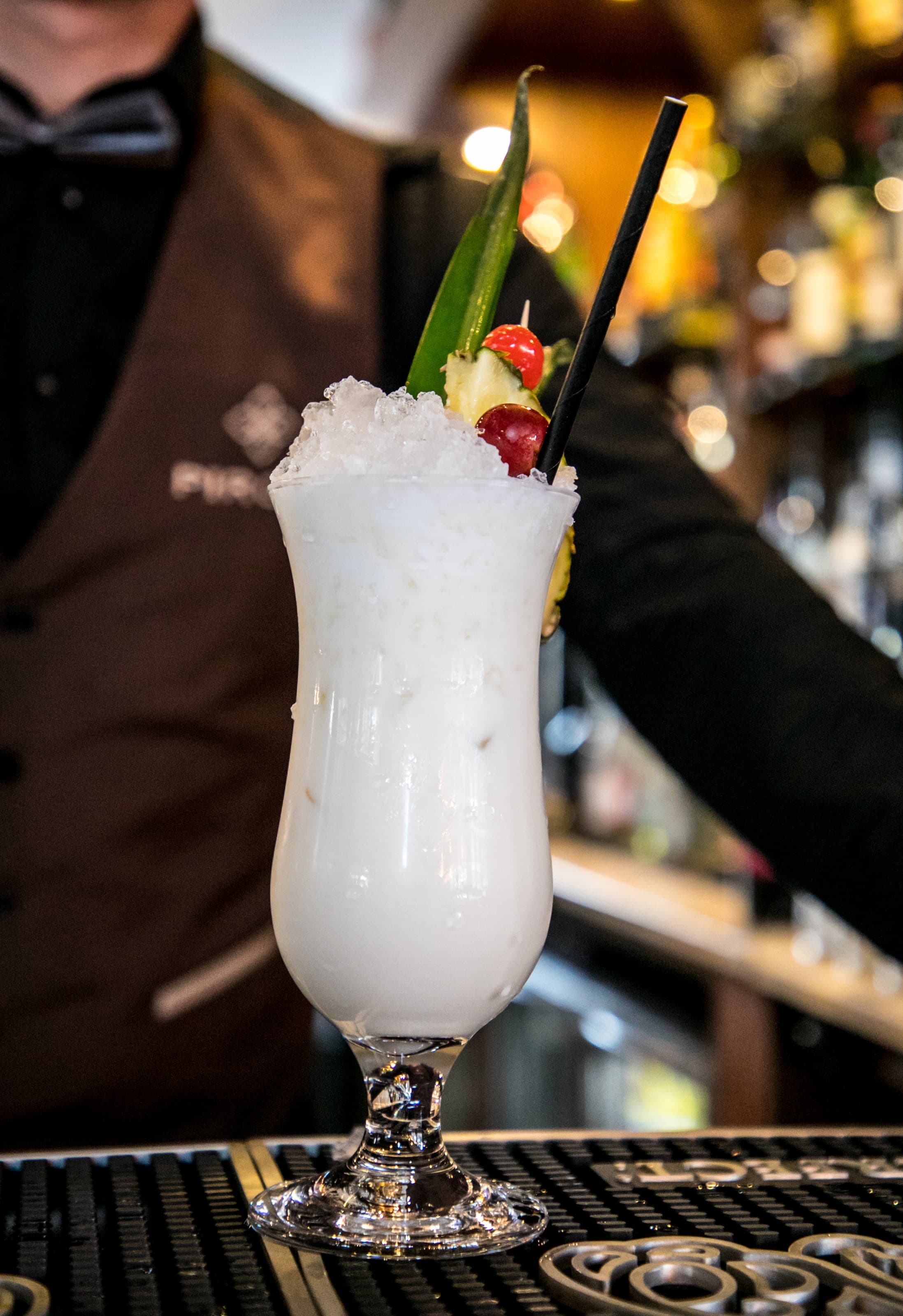A frozen white cocktail with a cherry on the bar