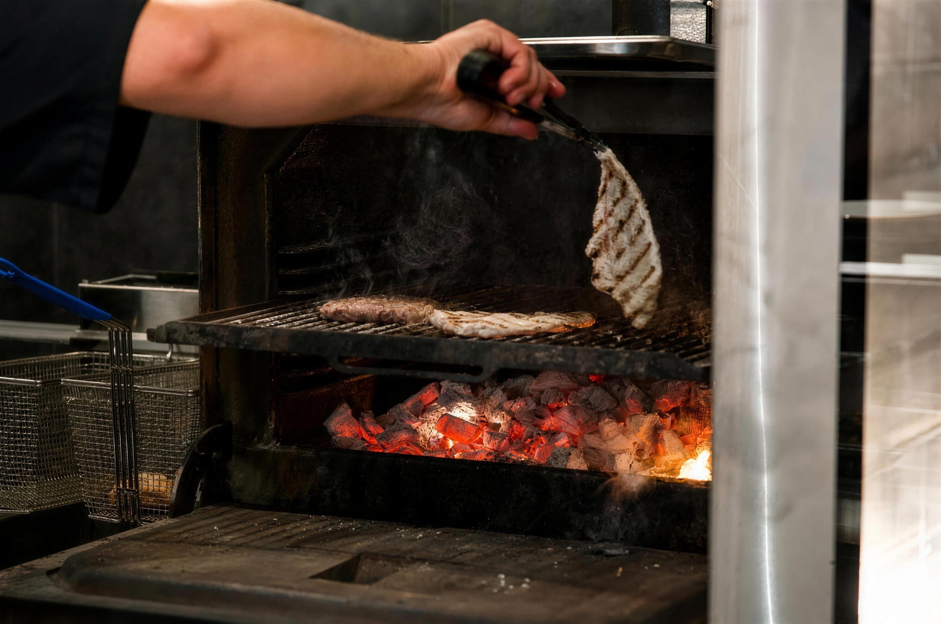 Meat being turned over a charcoal grill