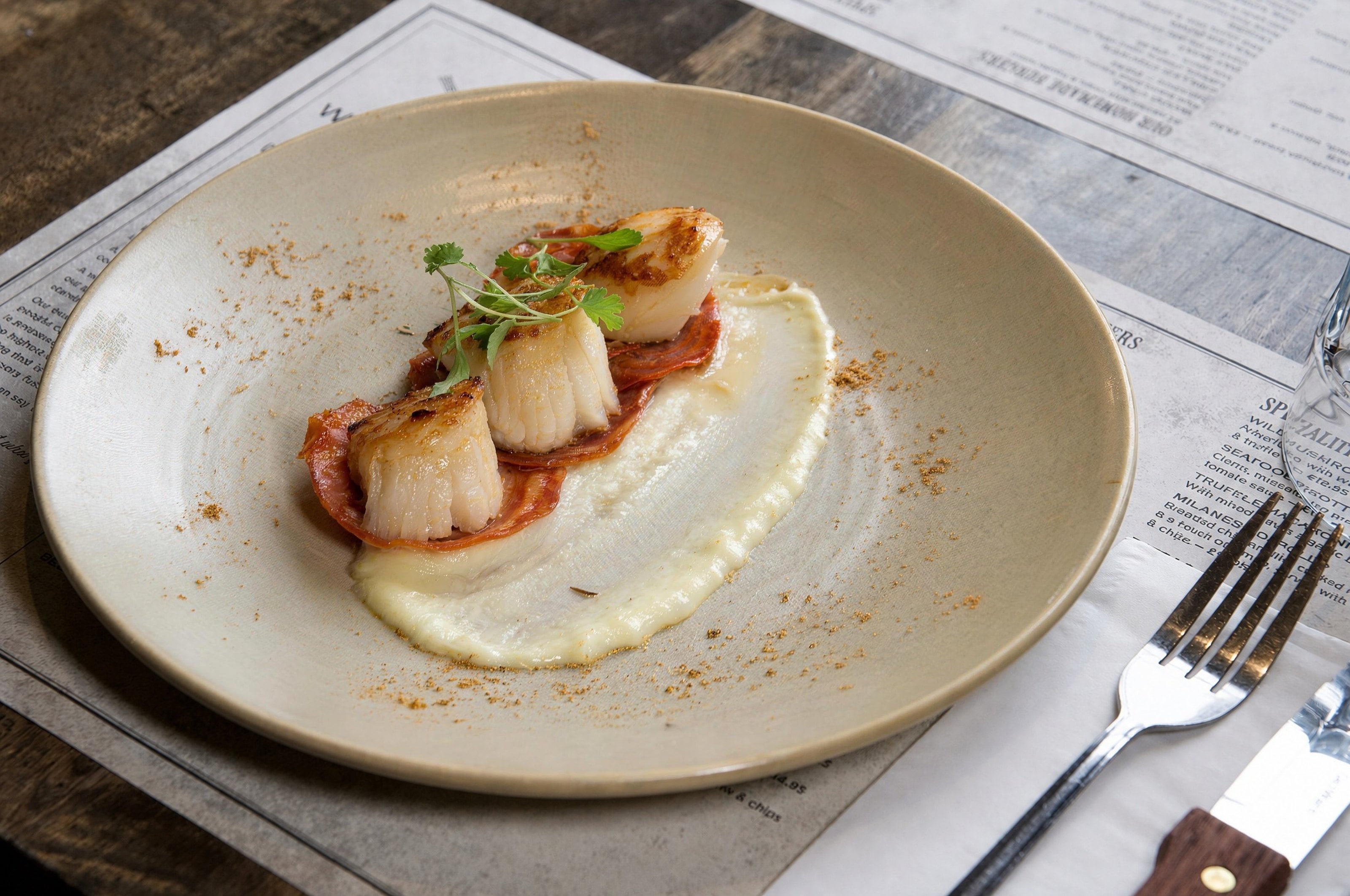 Seared scallops on a purée, plated in a restaurant