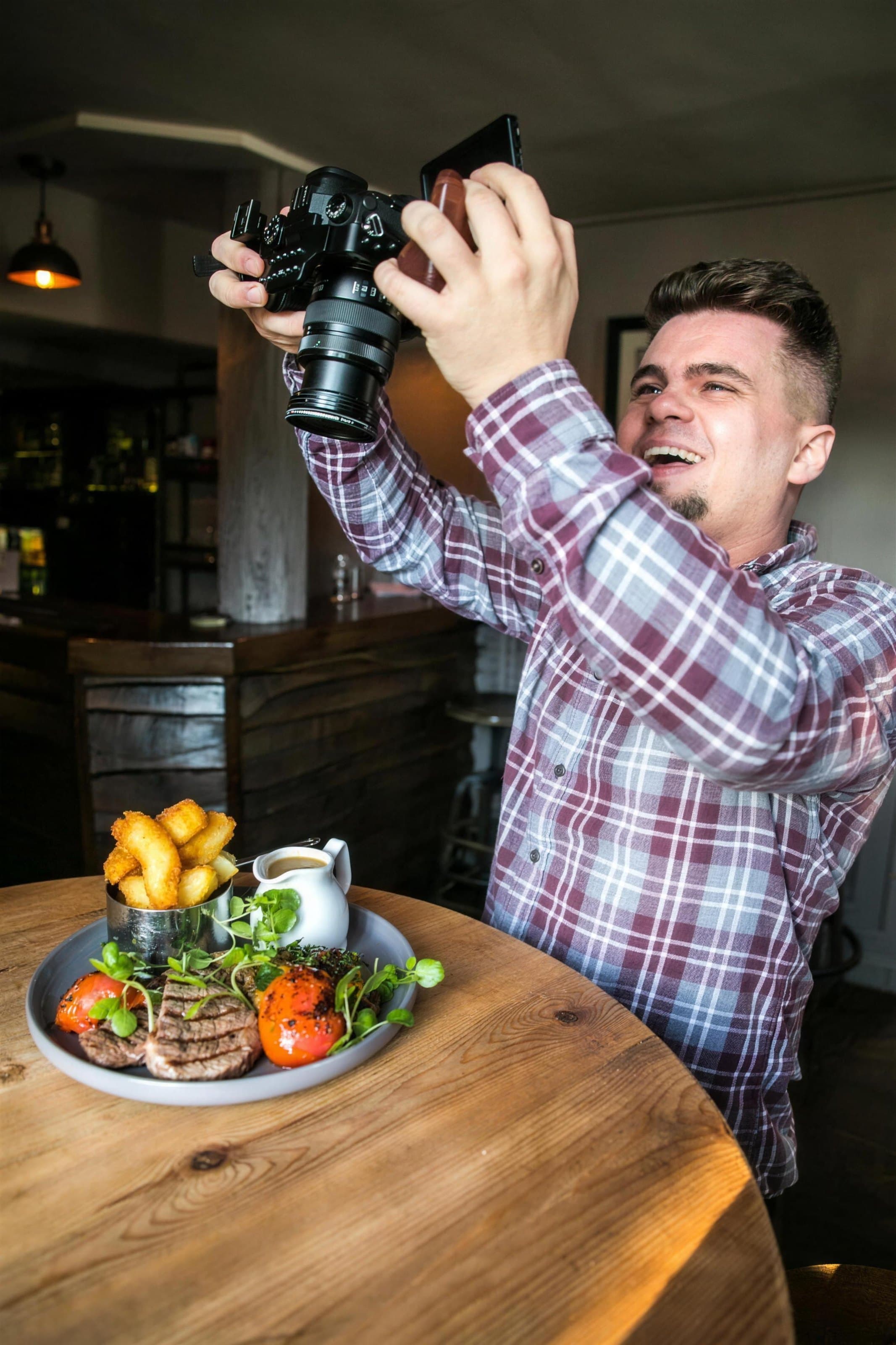 Louis with his camera at a restaurant table, laughing