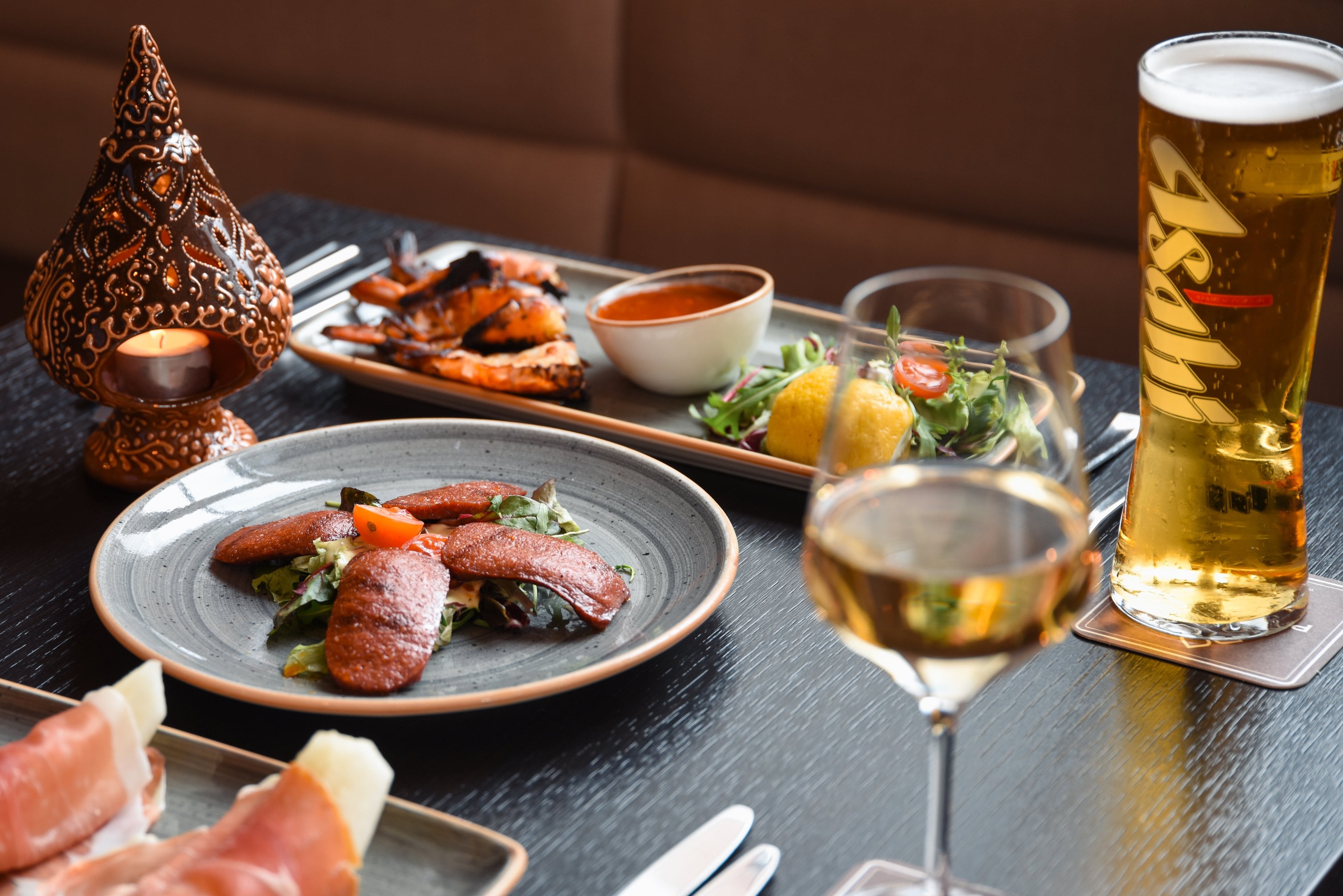 Grilled meats, salad, wine and a pint on a candlelit restaurant table