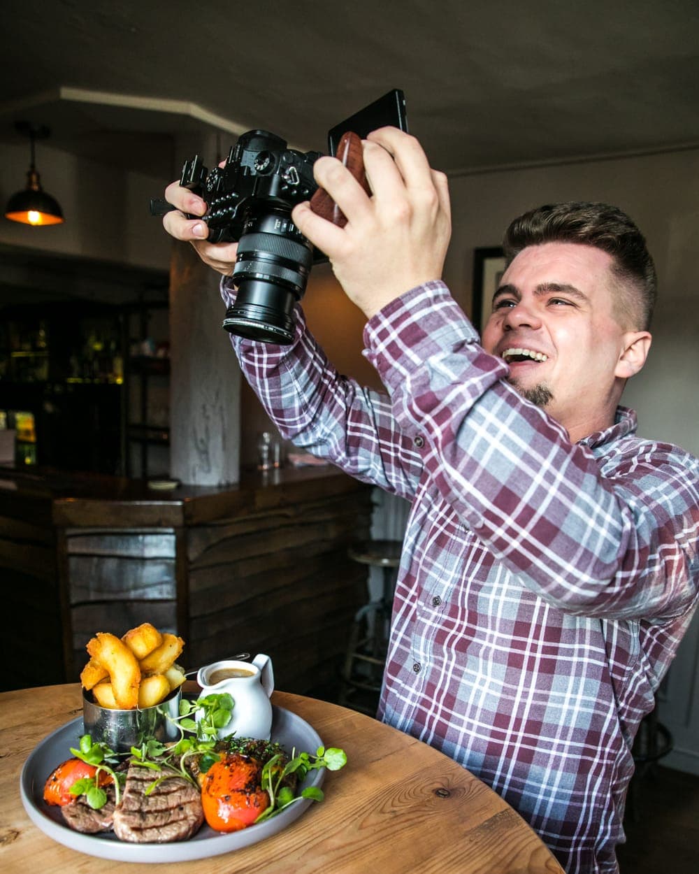 Louis Hopkins photographing a steak dish in a restaurant
